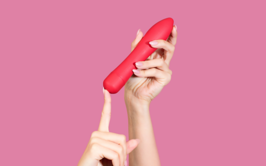 pink background hand holding red dildo